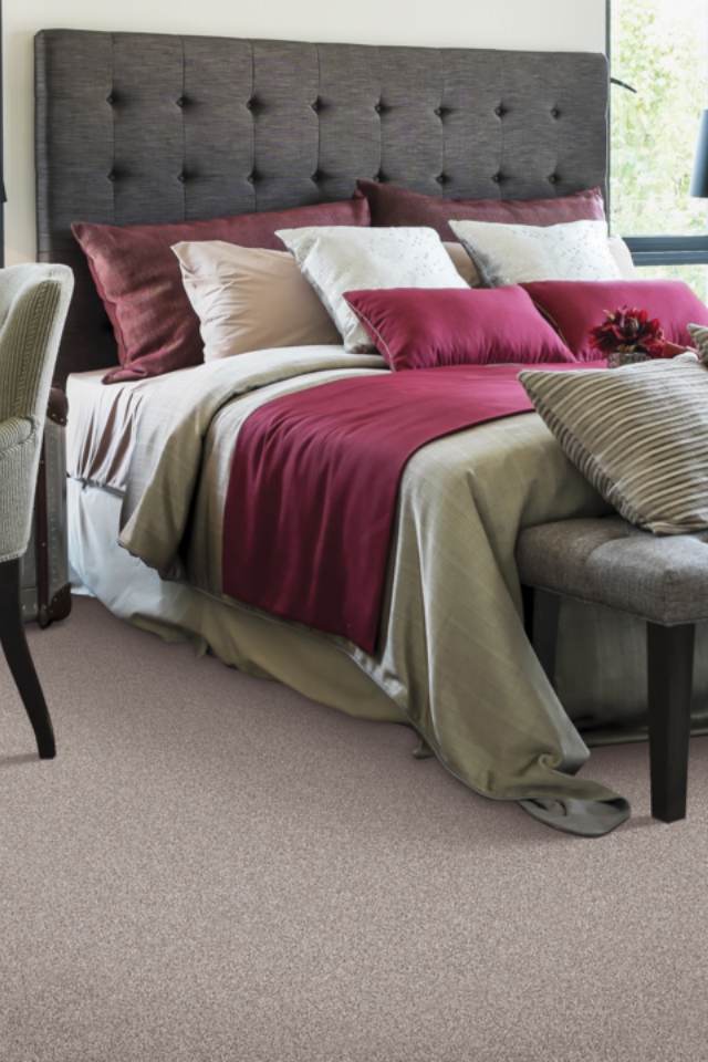 Deep red accent pillows and blanket on neutral bedding in bedroom.